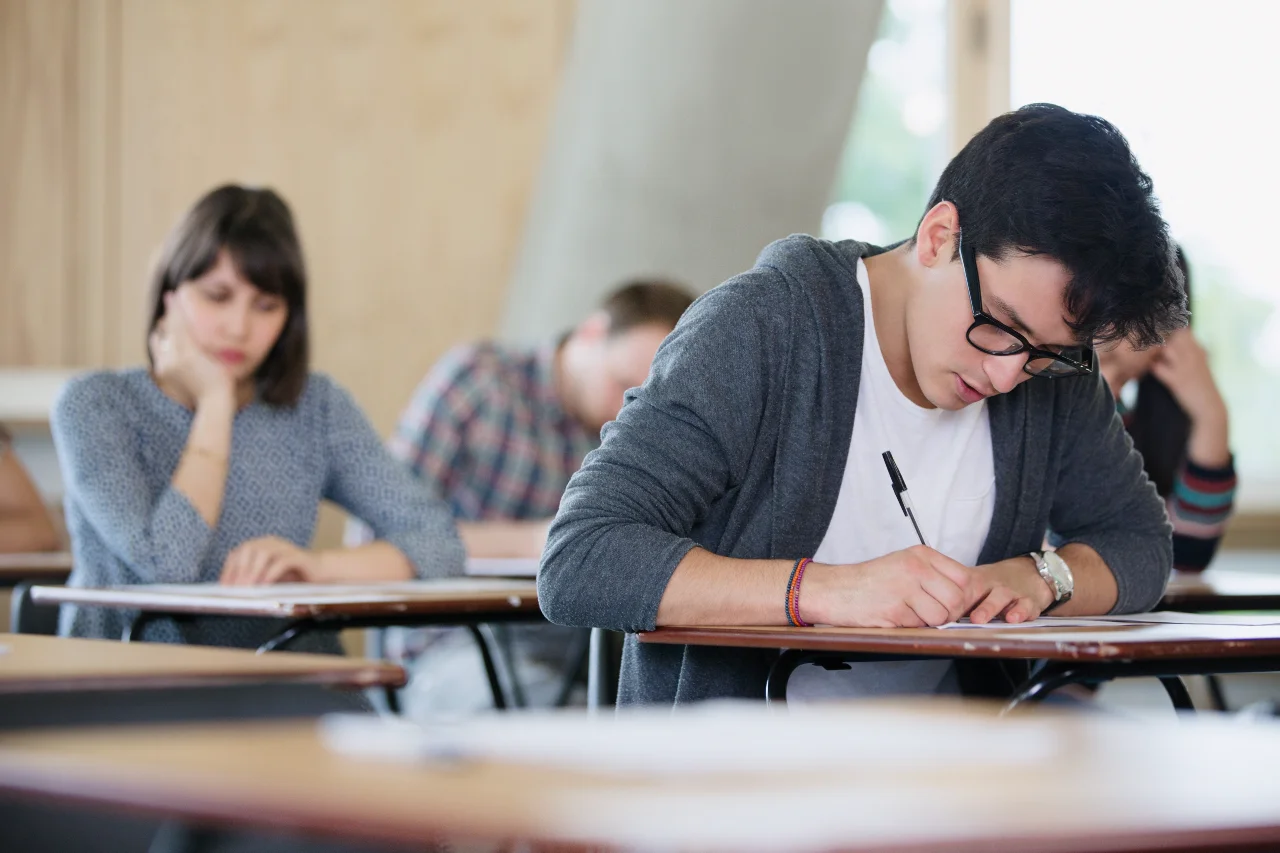 Students sitting an exam at individual desks in a classroom